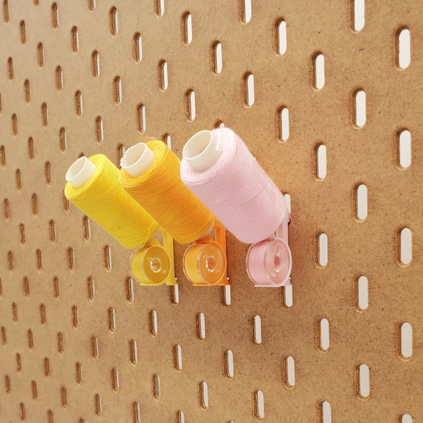 Savannah Yellow, Sunrise Orange, Light Pink angled thread and bobbin storage for SKADIS Pegboard