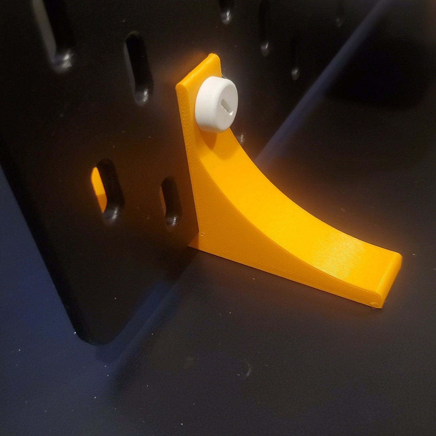 Orange normal Desktop support stands on a black SKADIS board